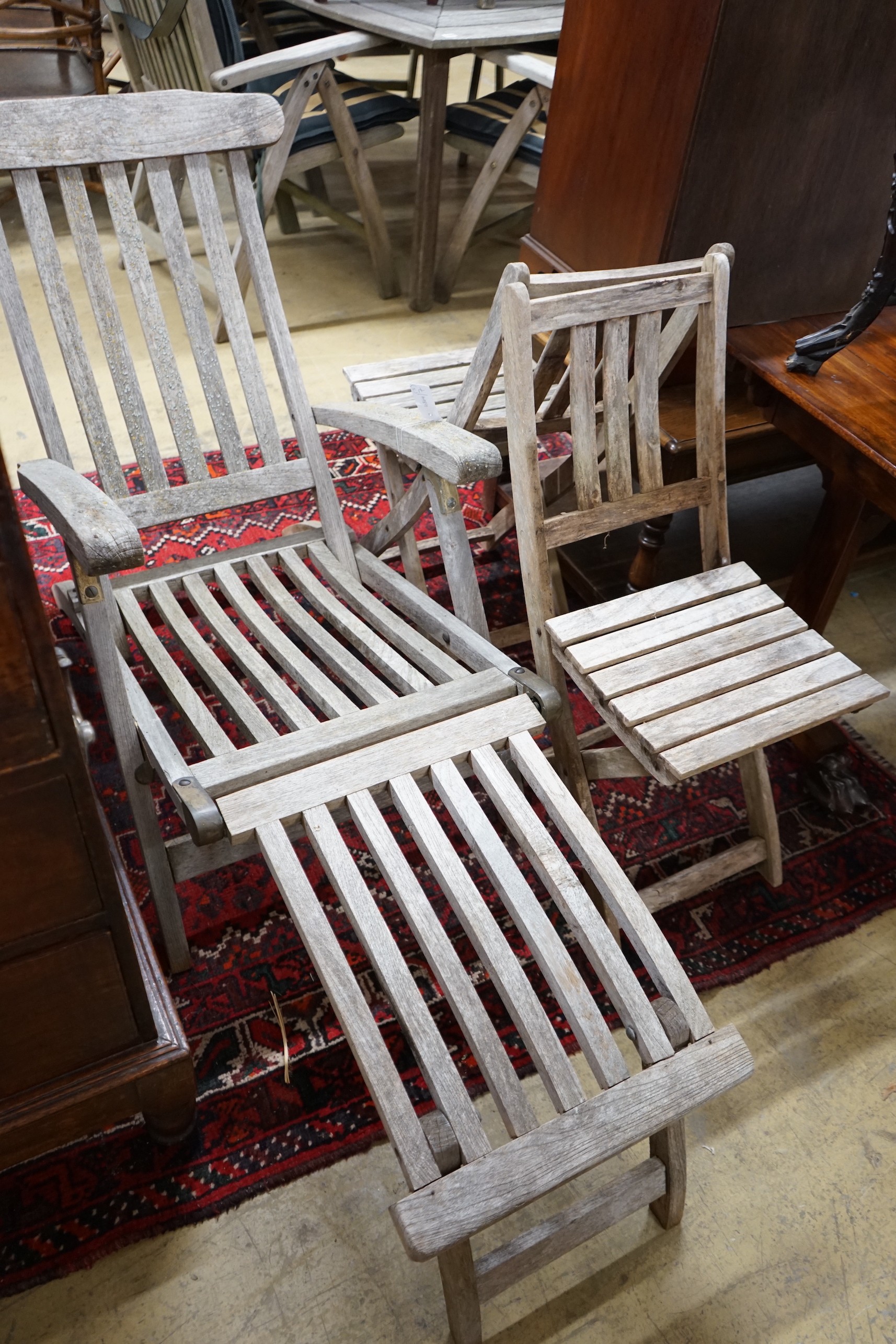 A weathered teak garden steamer chair and two folding garden chairs